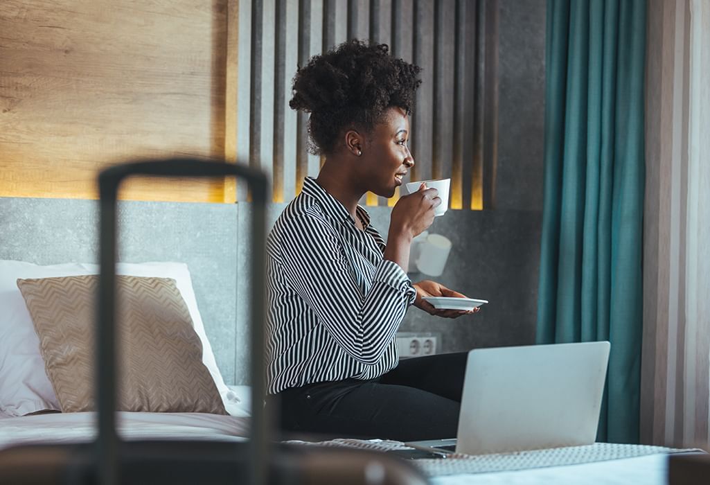 business woman siting near her laptop sipping on coffee