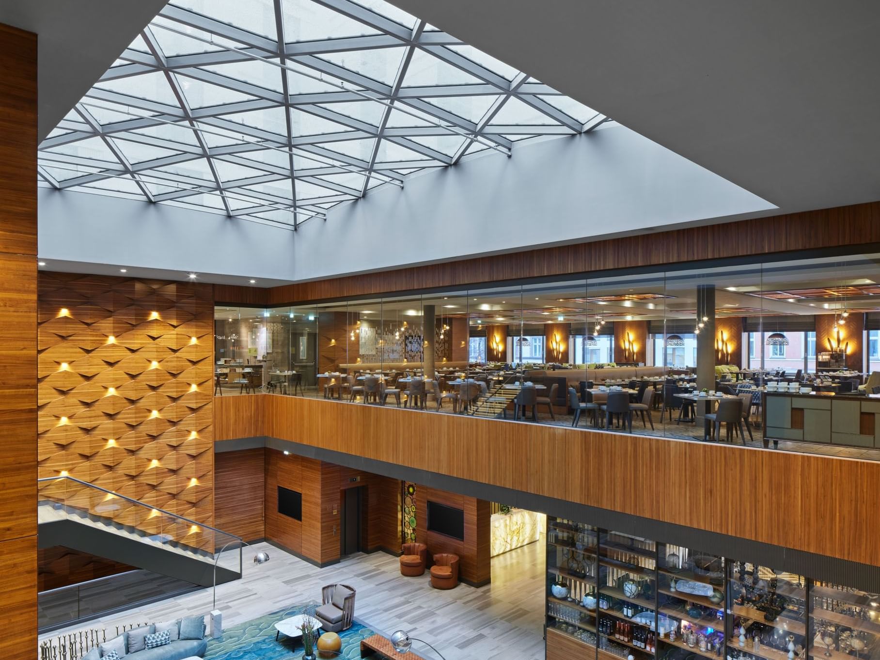 Moderne Hotellobby mit kristallinem Glasdach, stilvollem Sitzbereich und angrenzenden Restaurants – Titanic Chaussee Berlin