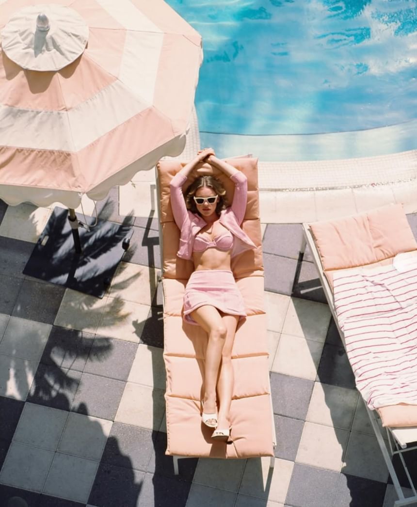 Overhead view of a woman in a pink outfit relaxing on a lounge chair by the pool at The Plymouth Hotel South Beach