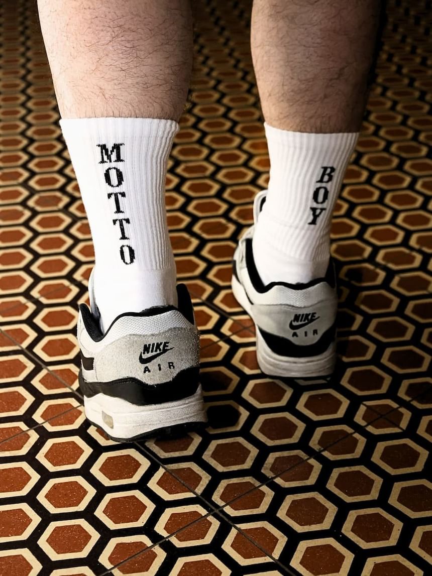 Weiße Socken mit der Aufschrift Motto Boy vom Hotel Motto Merch