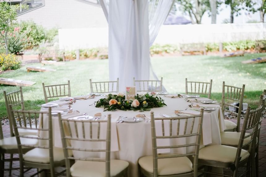 Elegant outdoor wedding reception table with white linens, and floral centerpiece at Aramark Chauncey Conference Center