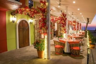 Outdoor terrace with colorful autumn foliage, arched doorways, and dining tables at sunset at Playa Los Arcos Puerto Vallarta