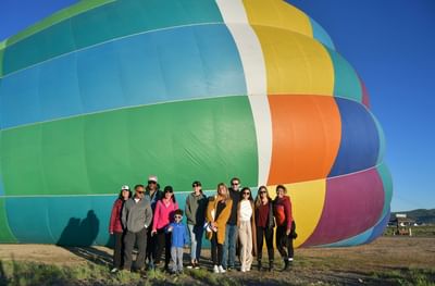 A group of people posing in front of a colorful hot air balloon near Hotel Park City Autograph Collection