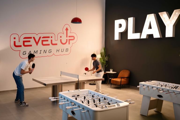 Two guests enjoy an exciting table tennis match at the stylish Level Up Gaming Hub inside DAMAC Maison Aykon City