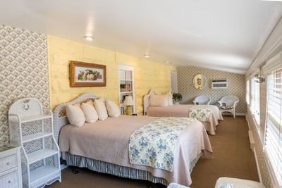 Modern room with cozy beds, featuring walls, floral wallpaper, and wicker furniture at The Ranch at UCross