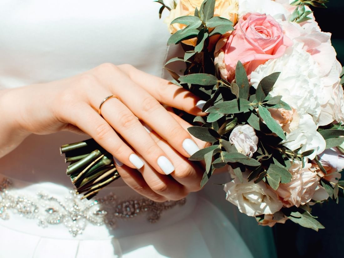 Vibrant bridal bouquet of yellow and pink roses held by a bride showing her wedding ring at The Sebel Mandurah