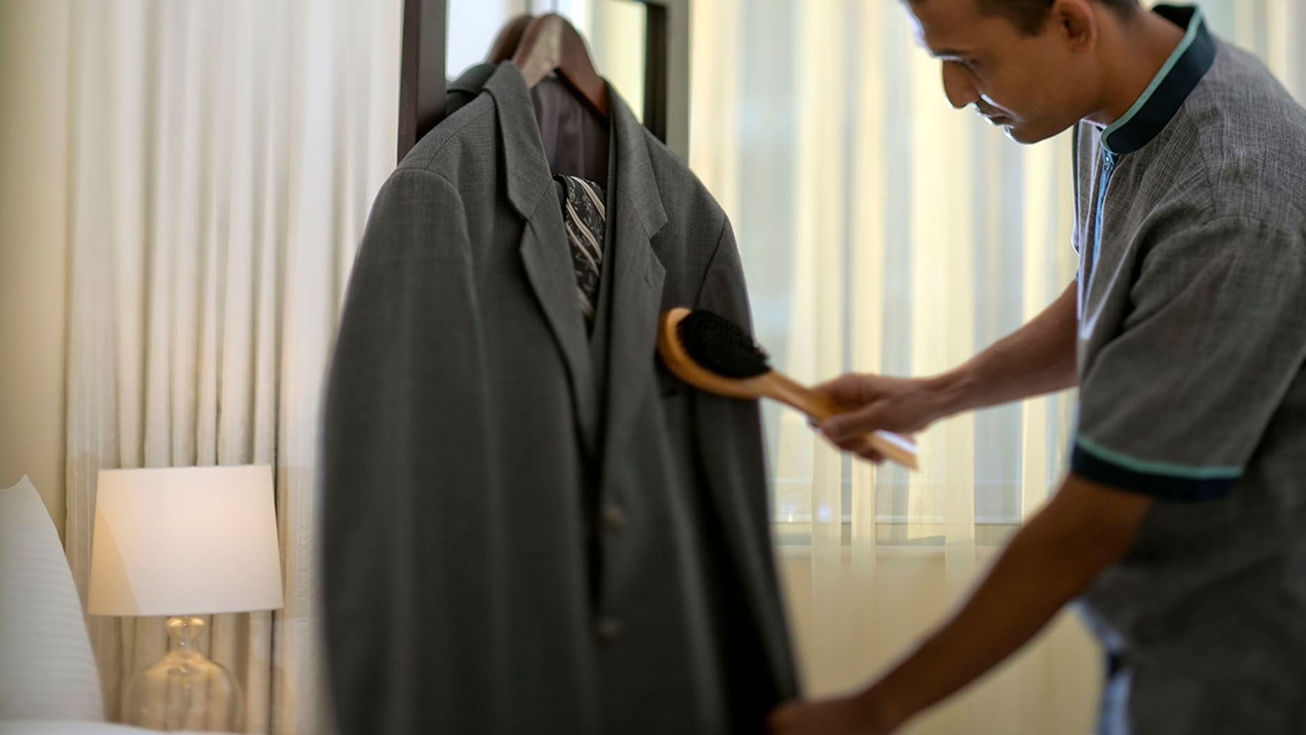 A man meticulously brushes a suit at DAMAC Maison Dubai Mall Street