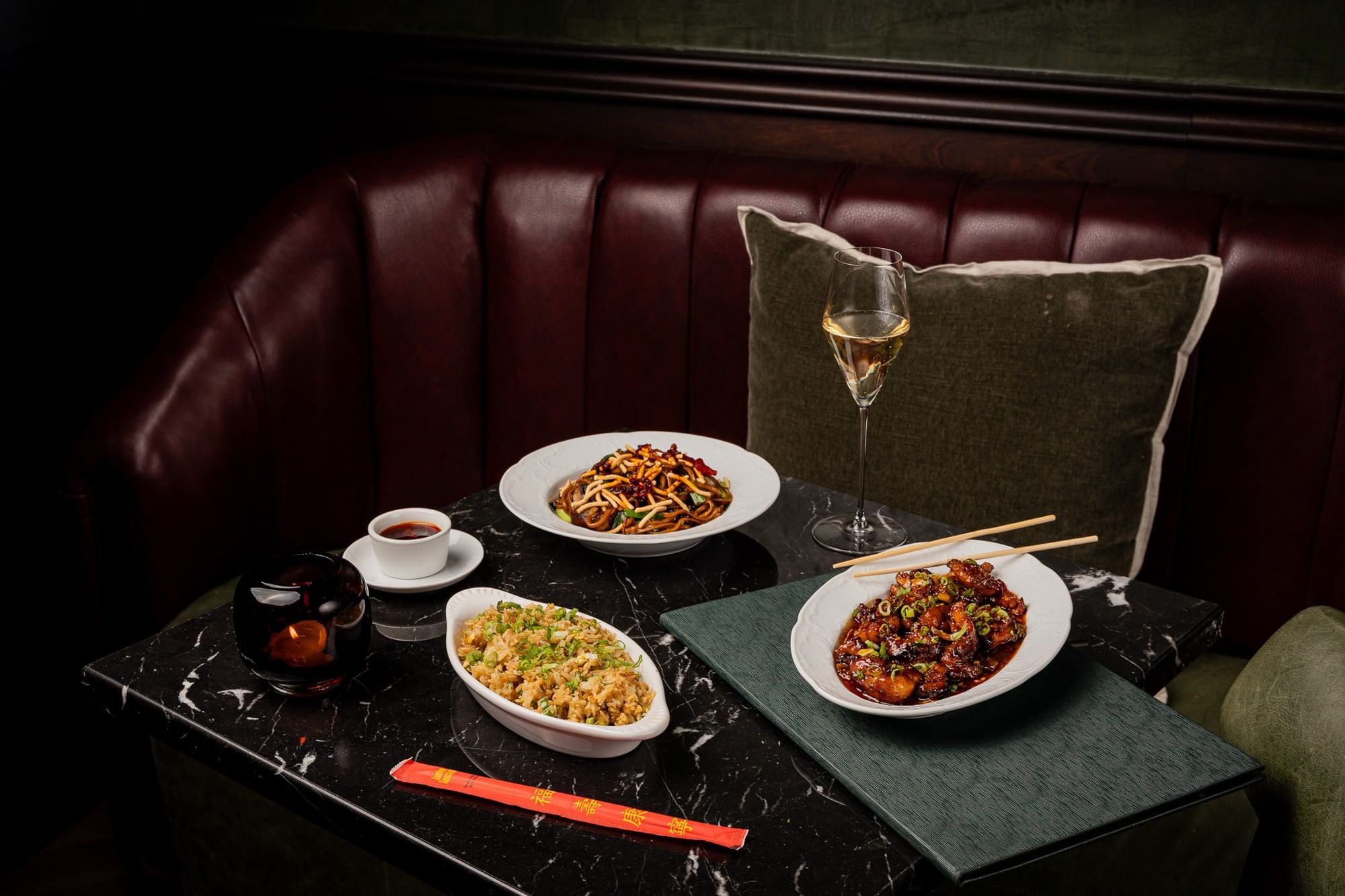 a table with chinese food and wine in a booth