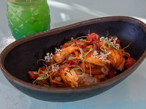 Seafood rice dish with peppers and tomatoes in an oval bowl served at Tortugas Restaurant in Hacienda Del Mar Los Cabos