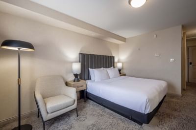 Standard Room with king bed, bedside tables, lamps and sitting area at Sandman Hotel & Suites Winnipeg Airport