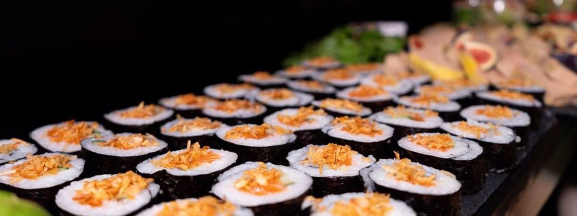 Long row of sushi rolls by a dark background under bright light in Sunday Brunch at Warwick Paris Champs Elysées