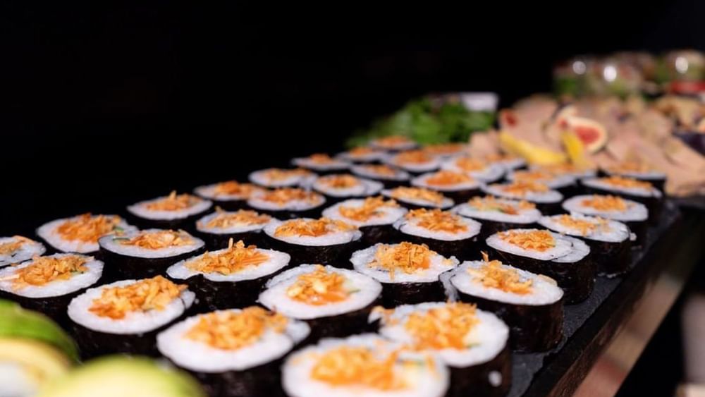 Long row of sushi rolls by a dark background under bright light in Sunday Brunch at Warwick Paris Champs Elysées