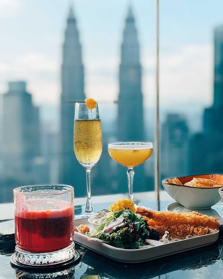 Close-up of a meal & cocktails served on a table in a Restaurant with KLCC view at Imperial Lexis Kuala Lumpur