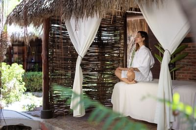 Elegant spa treatment room featuring white therapy tables and romantic, flowing white canopy curtains.