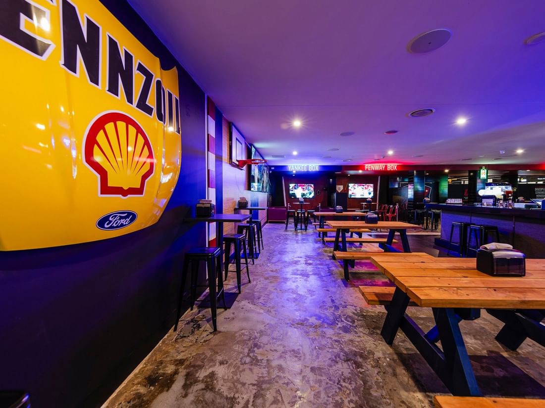 Wooden picnic tables and a large vintage Pennzoil display in KG Sport Bar at Mercure Brisbane King George Square