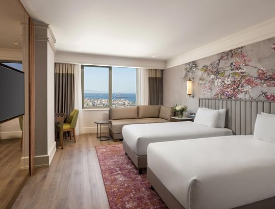 Titanic Port Bakırköy’de Deluxe Sea View Room’da ikiz yataklar, TV ve deniz manzaralı çalışma alanı.