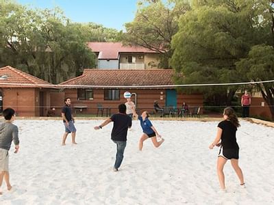 Group playing volleyball on a sandy court at UniLodge at Curtin University - Guild House.