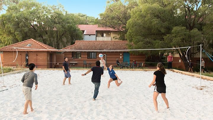 Group playing volleyball on a sandy court at UniLodge at Curtin University - Guild House.
