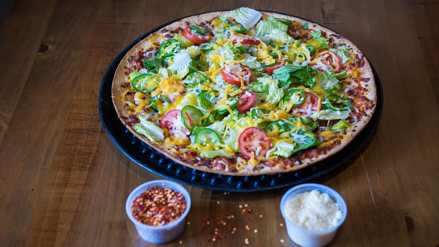 Close-up of Pizza served with salt and pepper in Bruno’s Pizza at Watersound Inn