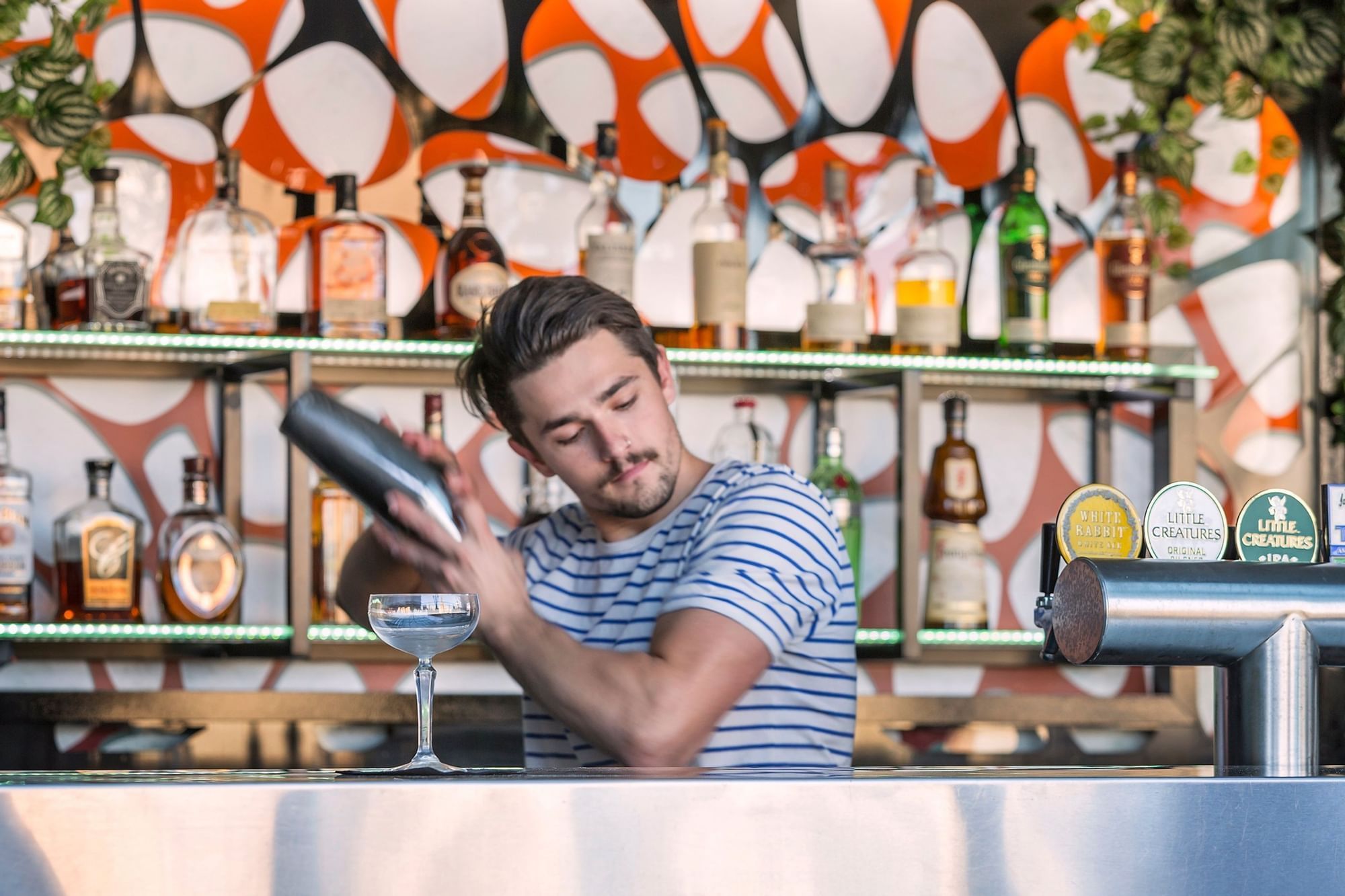 A bartender shaking a cocktail shaker in Sixteen Antlers Rooftop Bar at Pullman King George Square