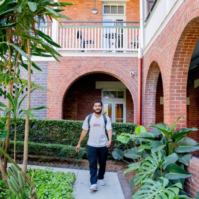 Student walking along pathway towards accommodation entrance.