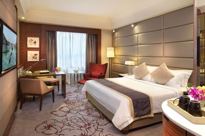 TV stand & work desk facing king bed in Superior with carpeted floors at One World Hotel