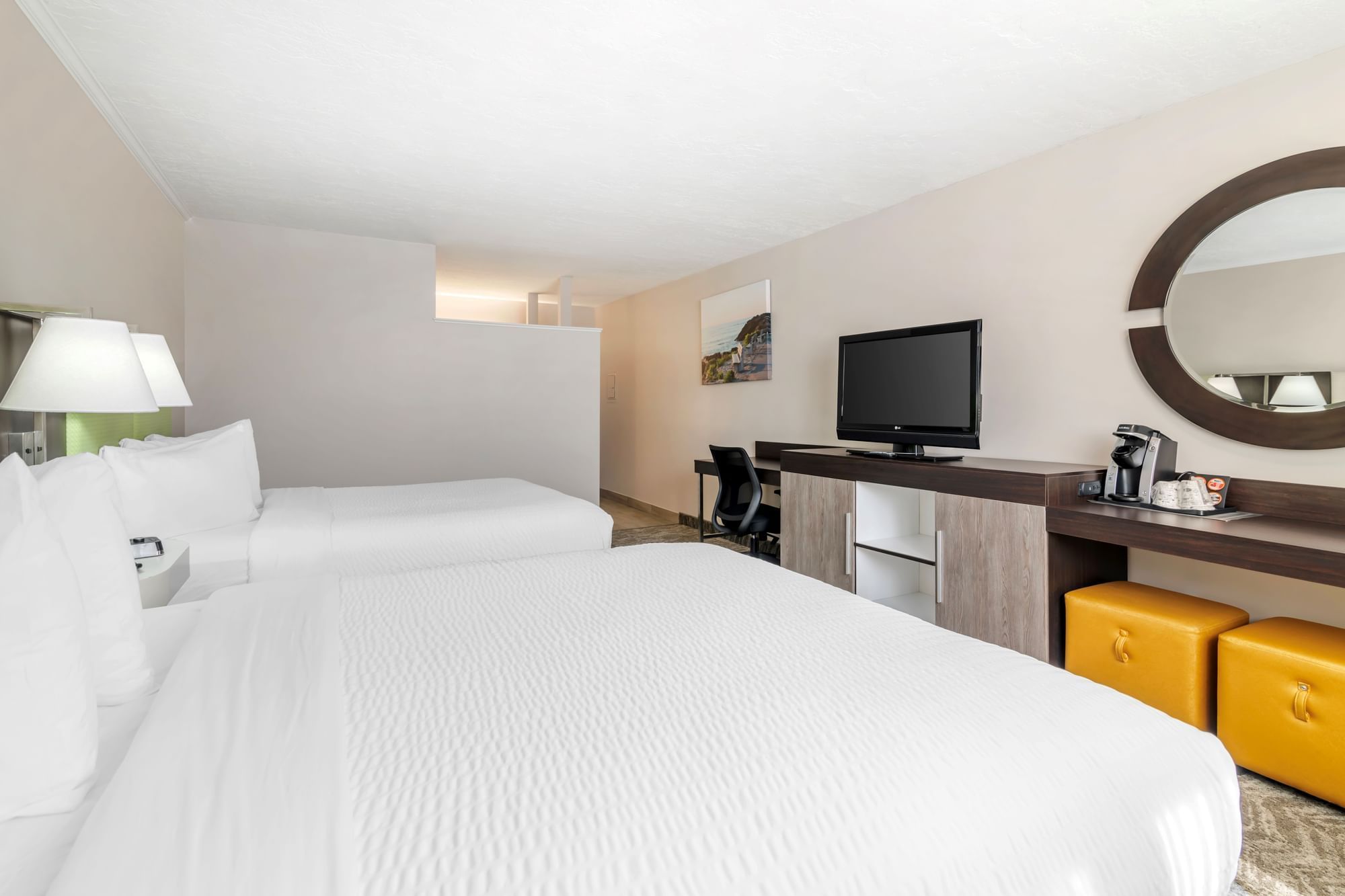 A hotel room with two queen beds, a desk, and a television