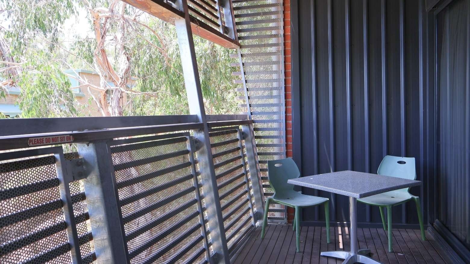 Outdoor balcony with a table and chairs at La Trobe University Hillside Apartments.