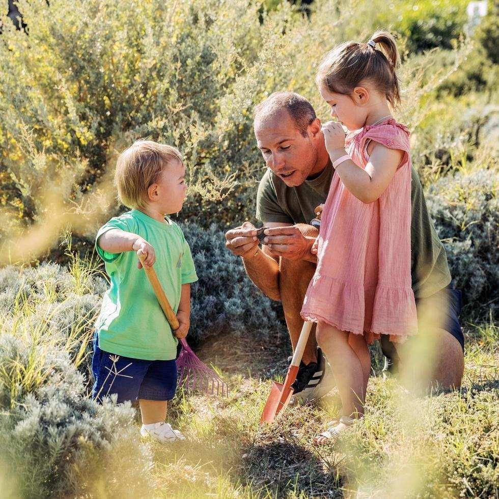 Father and two young children gardening together at Falkensteiner Family Resort Sicily