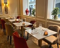 Le West Restaurant featuring plush chairs, set tables, and floral arrays by windows at Hôtel Westminster - Paris