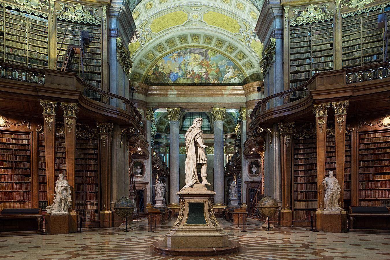 Prunksaal der Österreichischen Nationalbibliothek in Wien mit barocker Architektur und Bücherregalen.
