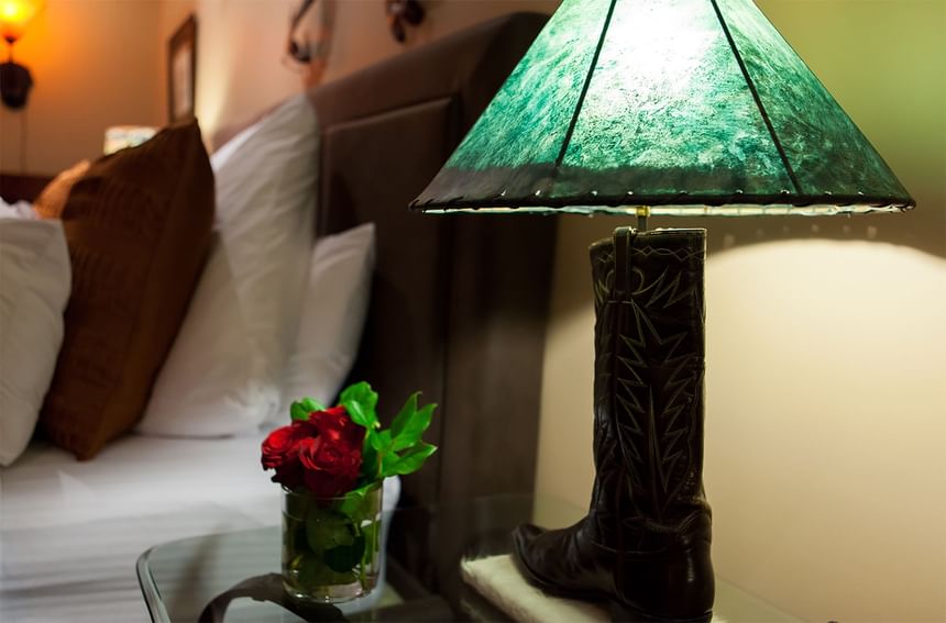 cowboy boot lamp on an end table with flowers in a vase