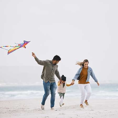 Family of three enjoying kite flying by the ocean - Lexis Port Dickson