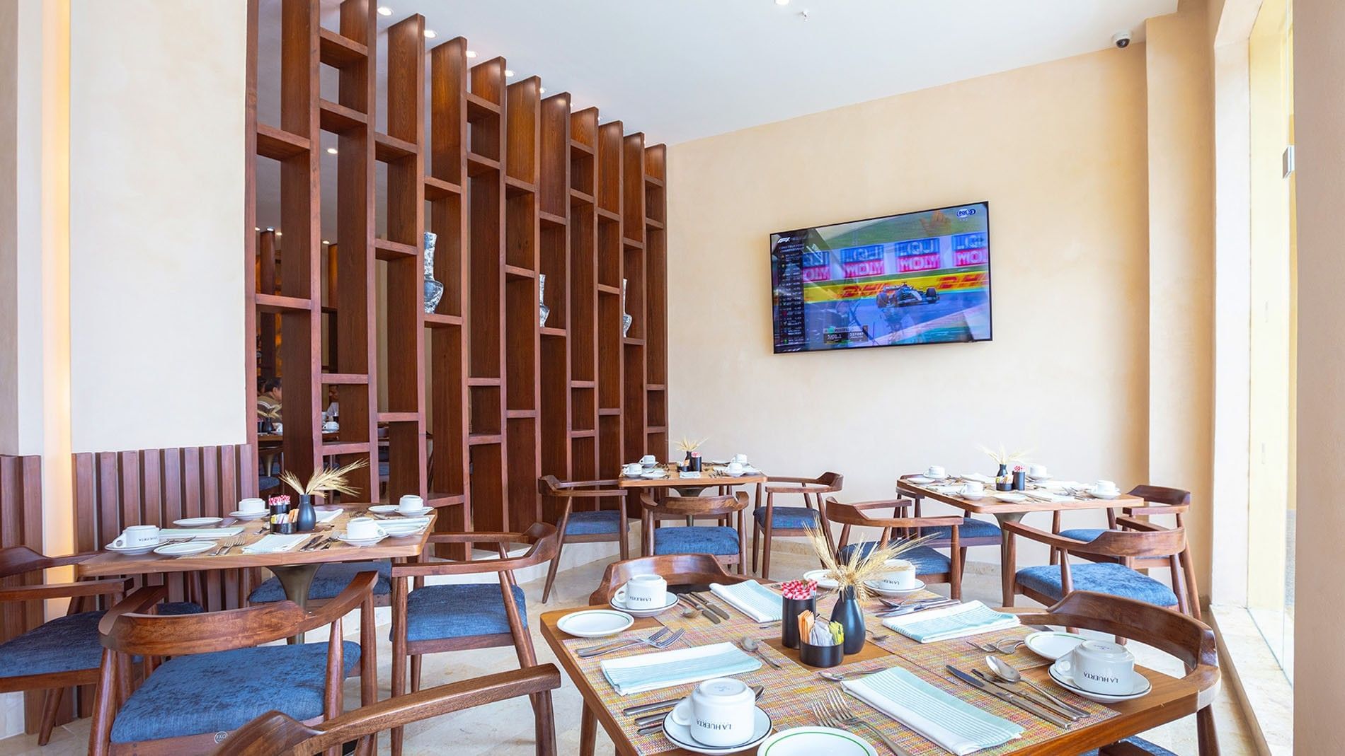 La Huerta restaurant seating with wooden partitions and a wall-mounted TV at Camino Real Acapulco Diamante