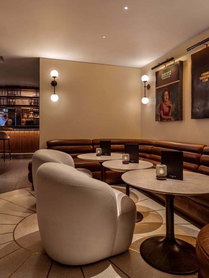 Leather seating and tables with lit candles in a stylish lounge area at The May Fair Bar