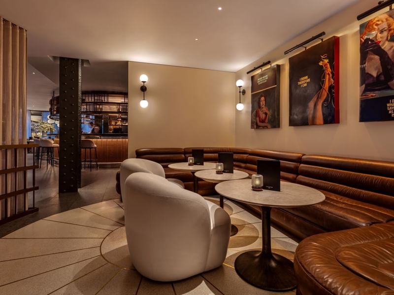 Leather seating and tables with lit candles in a stylish lounge area at The May Fair Bar