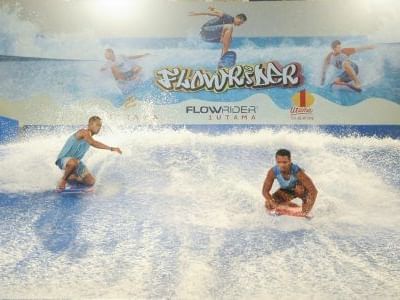Three people surfing on an indoor water park wave pool for vacation getaway in FlowRider near One World Hotel