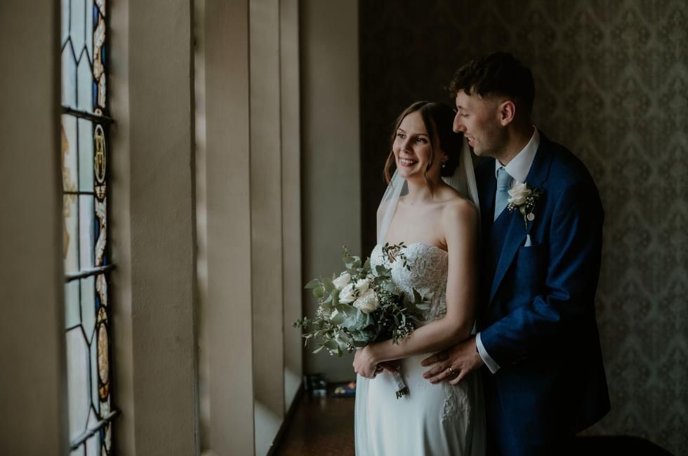Bride and groom looking outside window at Easthampstead Park, a fantastic wedding venue in Berkshire