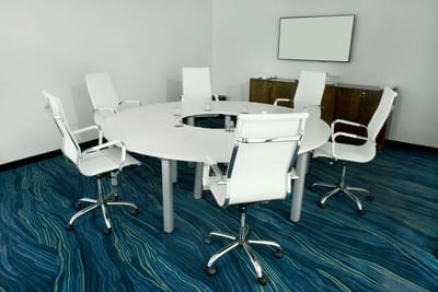 Little Room with circular table, chairs & carpeted floor with a blank wall-mounted screen at D Sabana Hotel