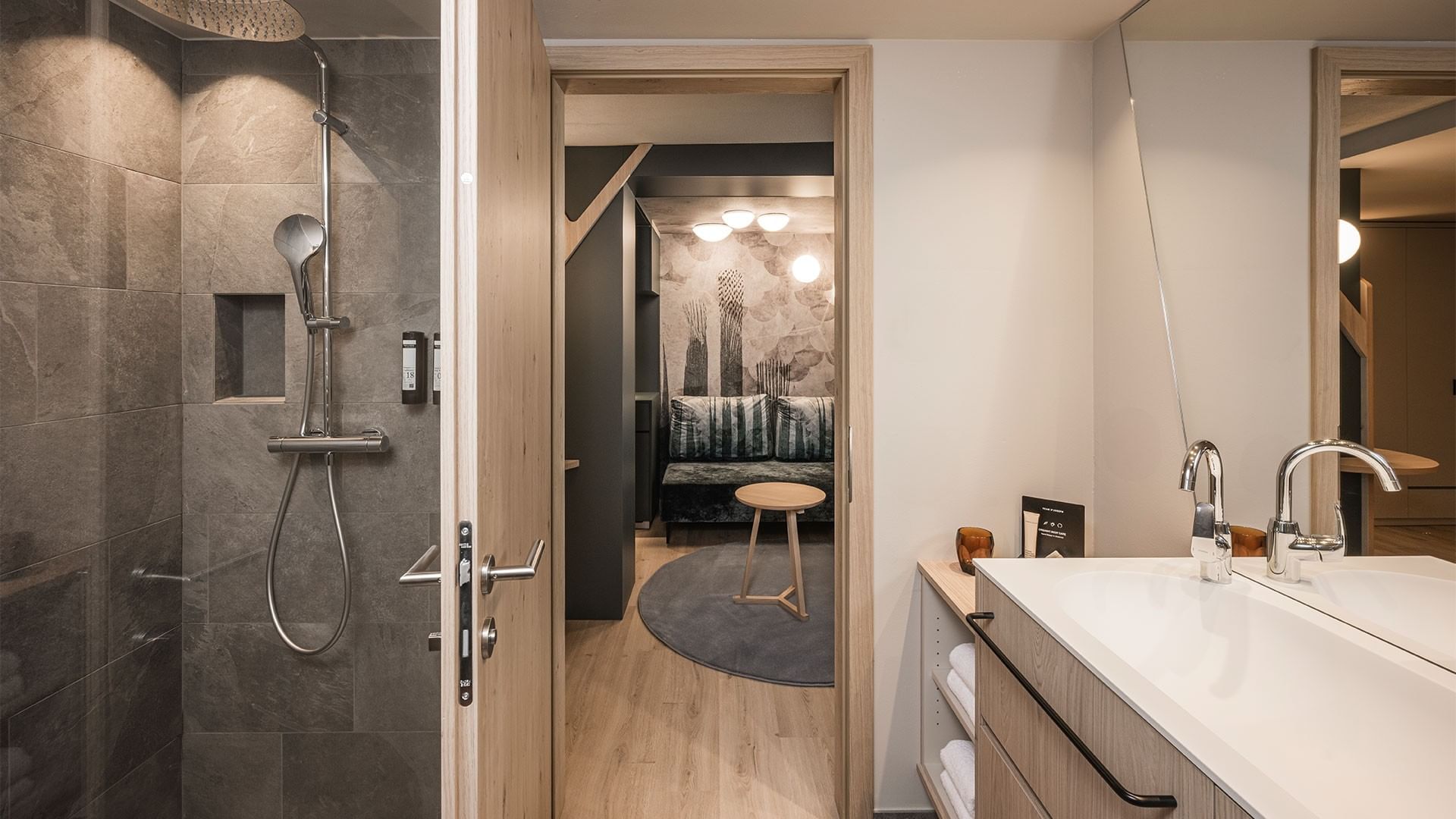 Modernes Badezimmer mit Dusche, Waschbecken und einem offenen Wohnbereich mit Couch.