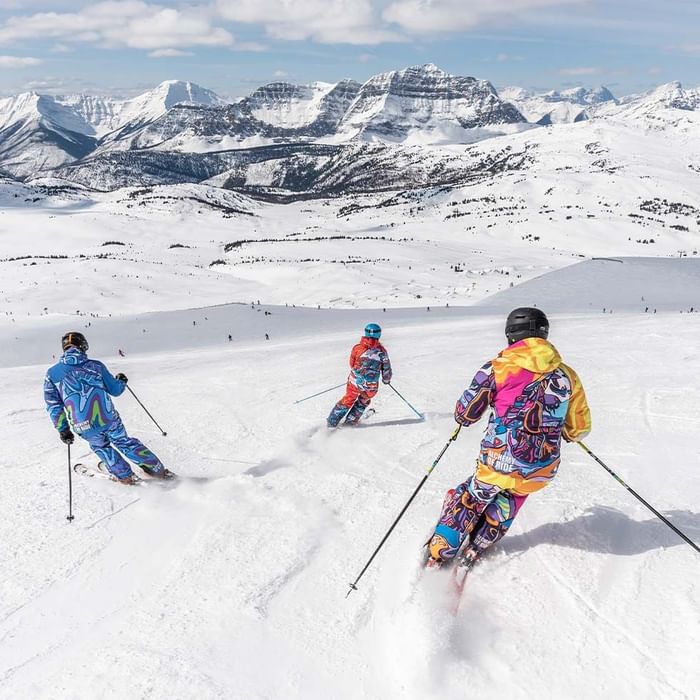 Skiers descending a snowy mountain slope with mountain backdrop near Falkensteiner Hotel Montafon