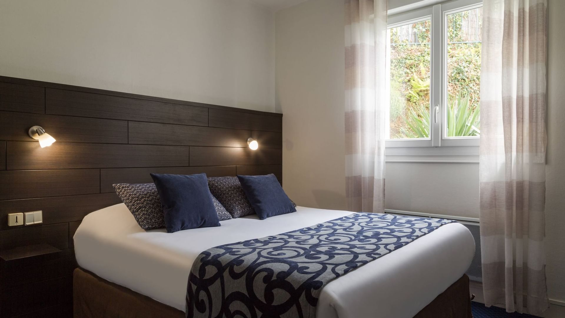 A comfy bed by a window in a bedroom at Originals Hotels