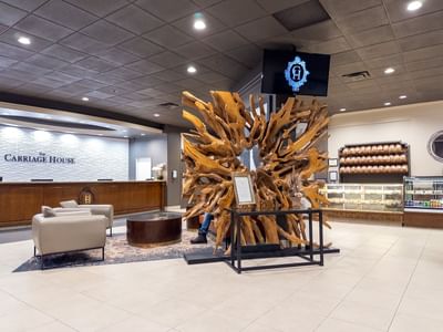 Lobby at Carriage House with large wooden sculpture and display cases with products.