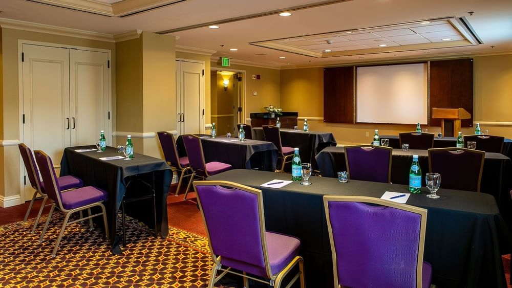 Purple chairs by black tables under a projector screen in Tabor at Warwick Denver