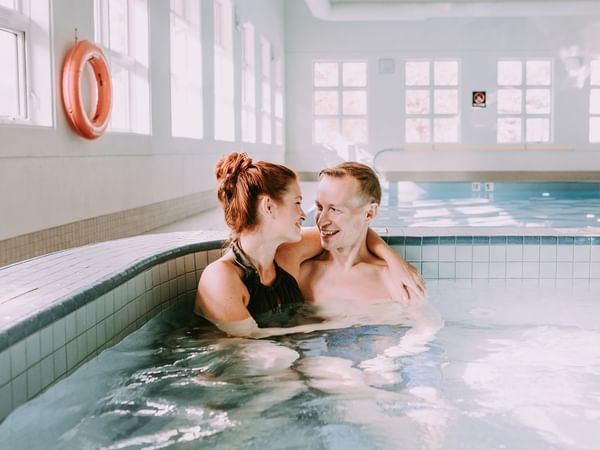 A couple in a hot tub smiling at each other.
