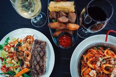 Steak and prawn dishes served with two wine glasses in Sola Restaurant at Fairwind Hotel Miami