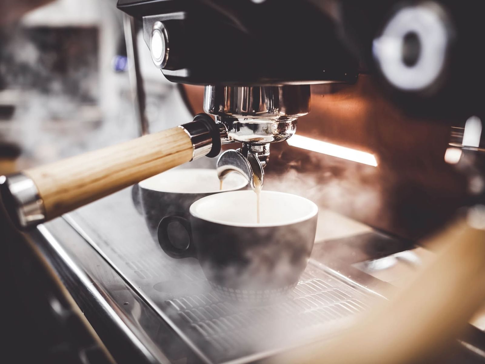 Close-up of an espresso machine brewing coffee into two cups in La Bottega Del Caffe near The Glam Hotel