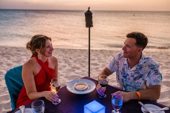 Couple dining at a beachside table in Passions on the Beach Restaurant near Amsterdam Manor Beach Resort Aruba
