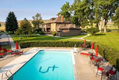 Refreshing outdoor swimming pool with a greenery view at The Ranch at UCross with table set-up