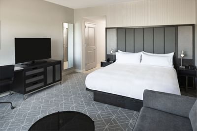 room with king bed, grey furniture and television